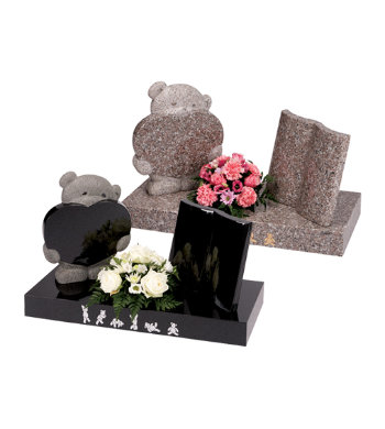 Black granite children’s headstone with small carved teddy bear with heart and book.